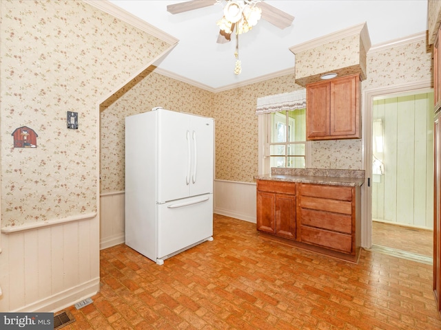 kitchen with visible vents, ornamental molding, wainscoting, freestanding refrigerator, and wallpapered walls