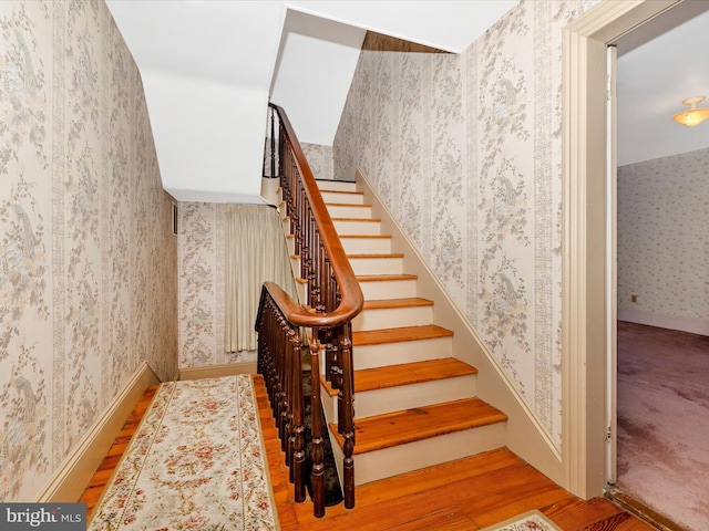 stairs featuring wallpapered walls, baseboards, and wood finished floors