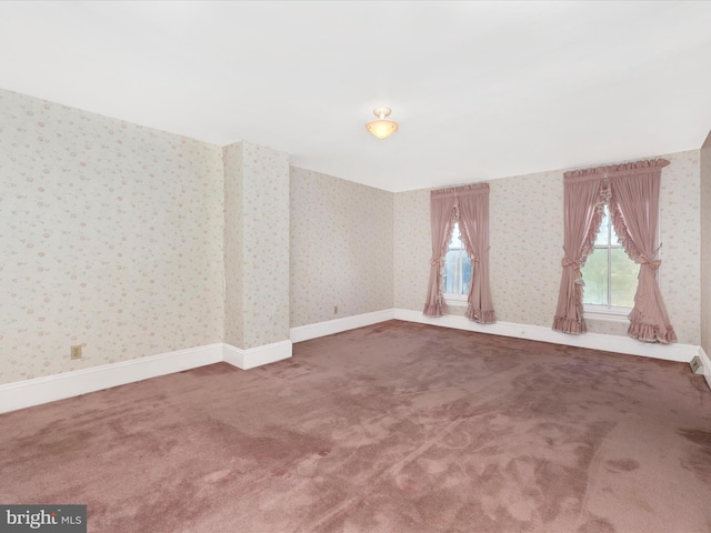 carpeted empty room featuring wallpapered walls and baseboards