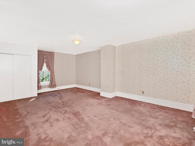 carpeted spare room featuring baseboards and wallpapered walls