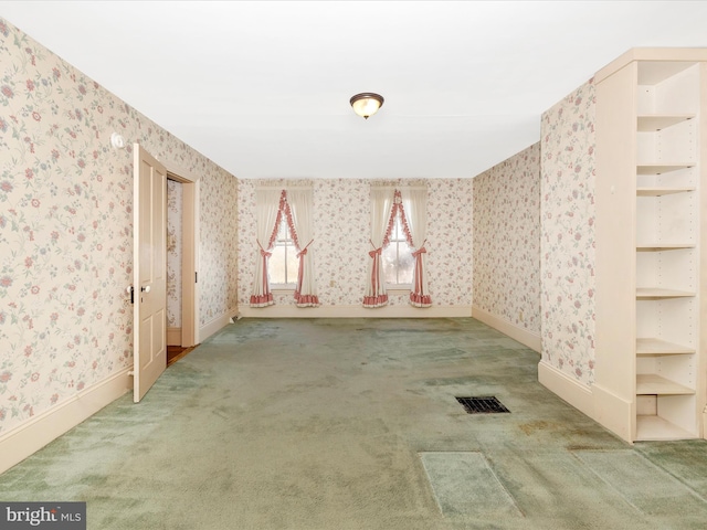 carpeted empty room featuring visible vents, baseboards, and wallpapered walls