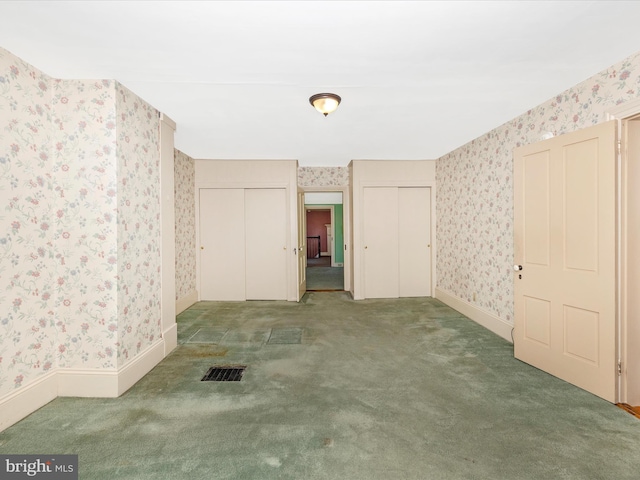 carpeted spare room with wallpapered walls, baseboards, and visible vents