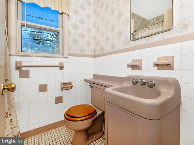 bathroom with wallpapered walls, wainscoting, toilet, tile patterned flooring, and vanity