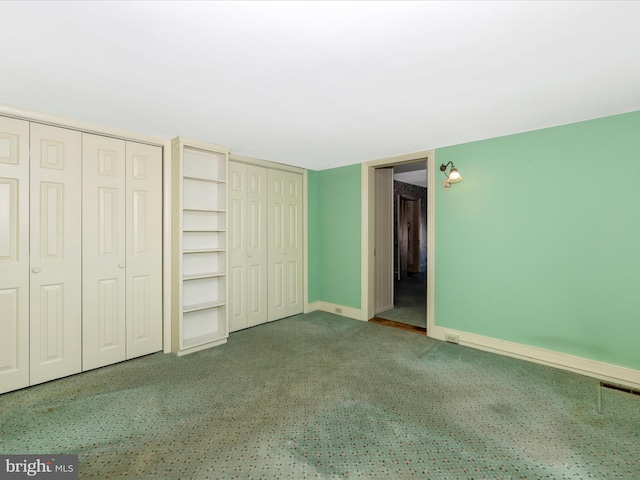 unfurnished bedroom featuring carpet floors, visible vents, baseboards, and multiple closets