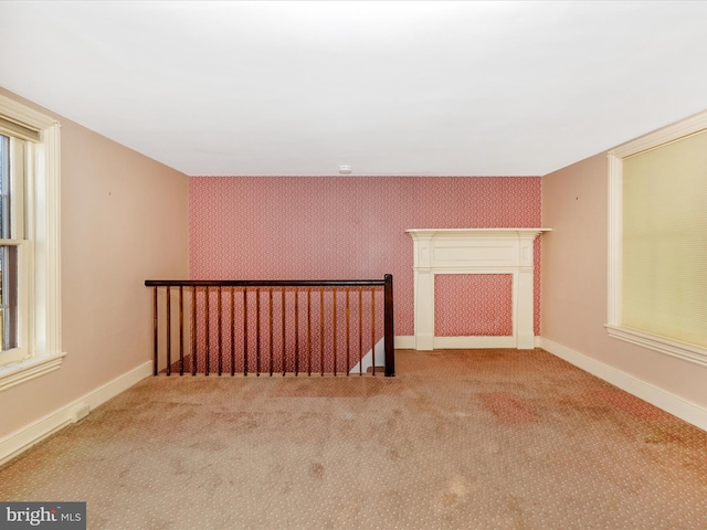 spare room with carpet floors, wallpapered walls, and baseboards