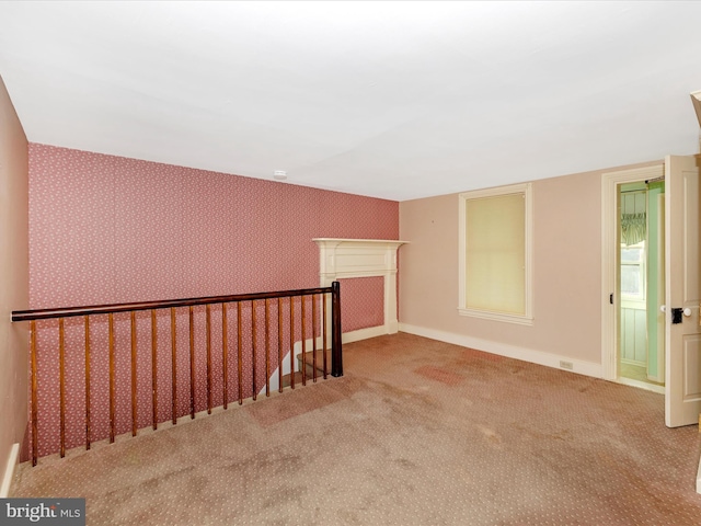 carpeted empty room with wallpapered walls and baseboards