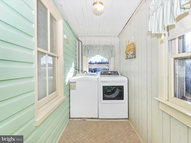 laundry room featuring light floors, laundry area, wooden walls, and washing machine and clothes dryer