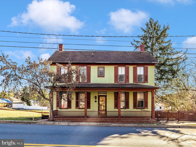 view of front of property with a fenced front yard, covered porch, and a chimney