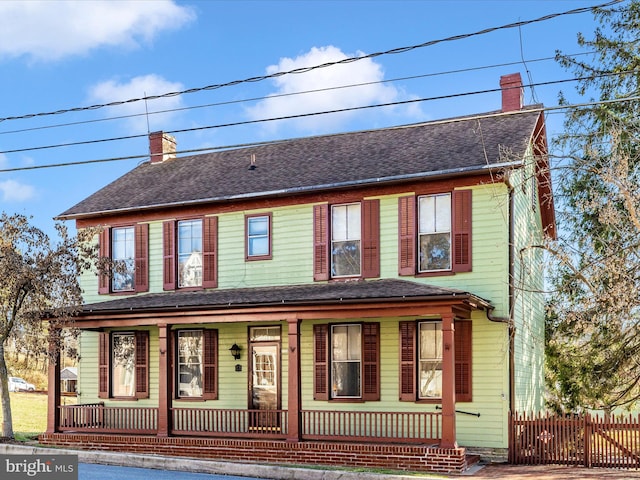 view of front of property featuring a porch, a chimney, a shingled roof, and fence