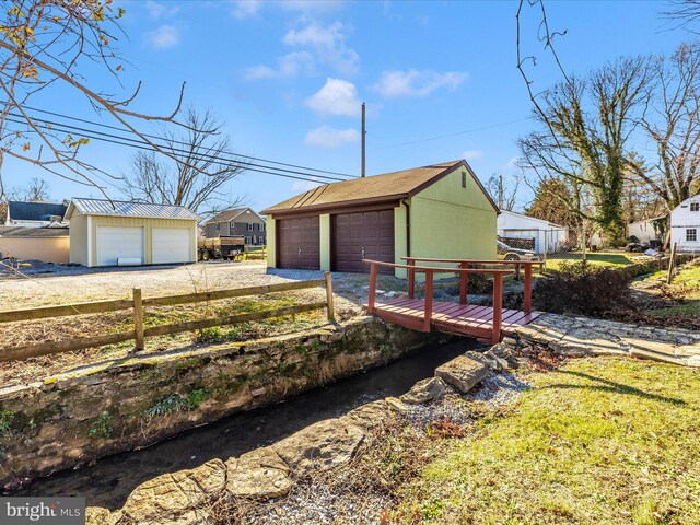 view of yard featuring an outdoor structure, a detached garage, and fence