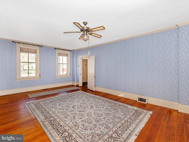 unfurnished room with wallpapered walls, wood-type flooring, and visible vents