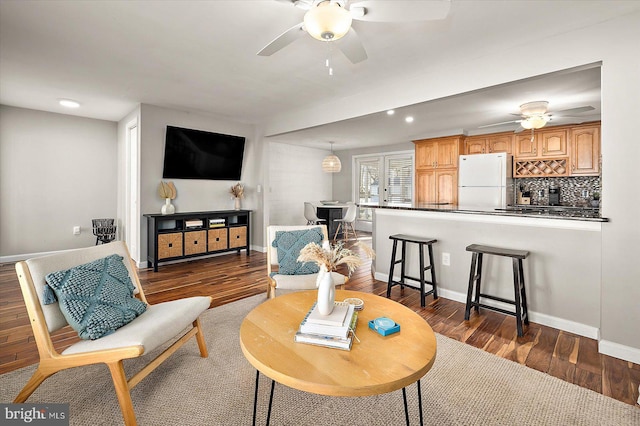 living room featuring ceiling fan and dark wood-type flooring