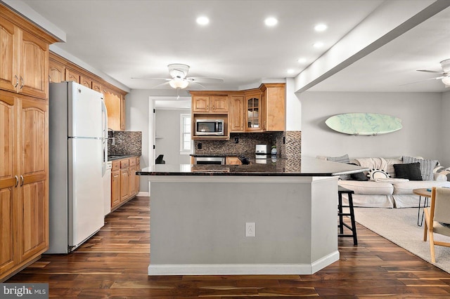 kitchen with kitchen peninsula, dark hardwood / wood-style flooring, stainless steel appliances, and a breakfast bar