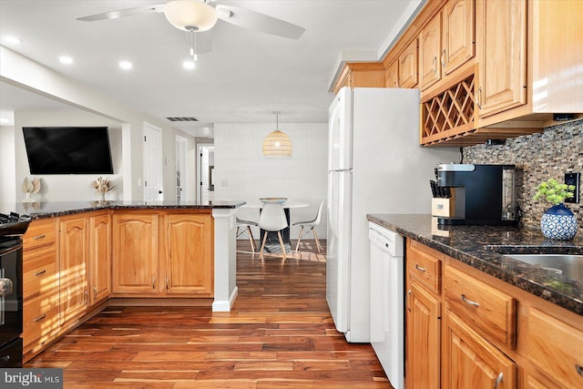 kitchen featuring hardwood / wood-style floors, dark stone counters, white dishwasher, ceiling fan, and kitchen peninsula