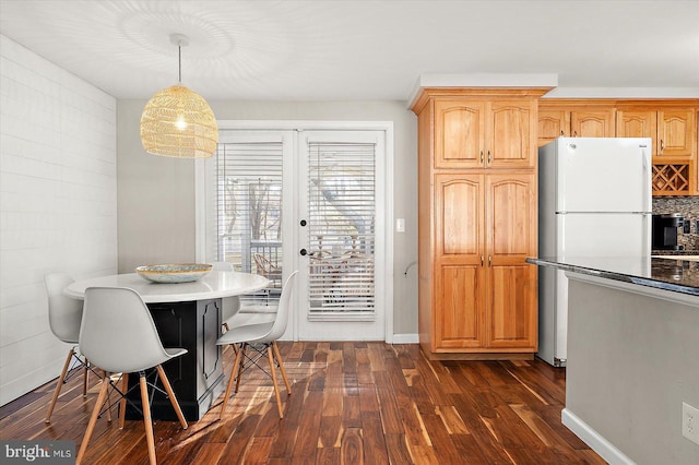 kitchen featuring french doors, hanging light fixtures, dark wood-type flooring, white refrigerator, and a kitchen bar