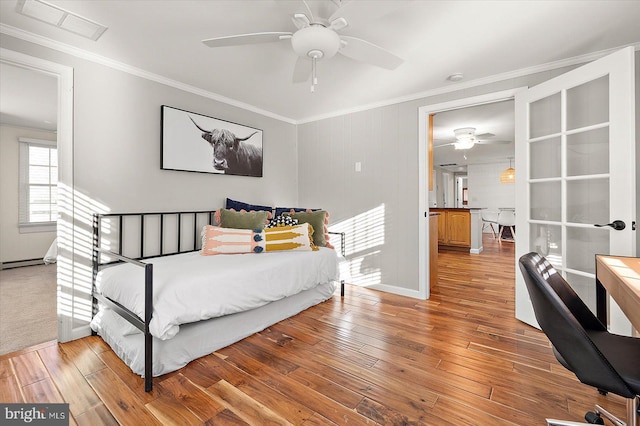 bedroom with wood-type flooring, a baseboard heating unit, ceiling fan, and ornamental molding