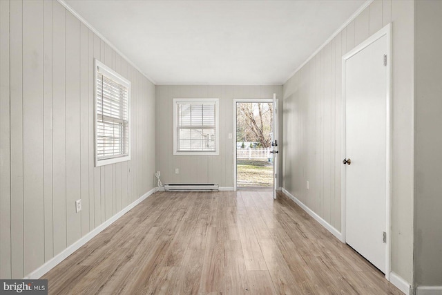 unfurnished room with wooden walls, light hardwood / wood-style flooring, a baseboard radiator, and ornamental molding