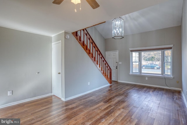 unfurnished living room with ceiling fan with notable chandelier, wood-type flooring, and ornamental molding