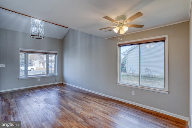 spare room featuring ceiling fan with notable chandelier, light wood-type flooring, and a healthy amount of sunlight