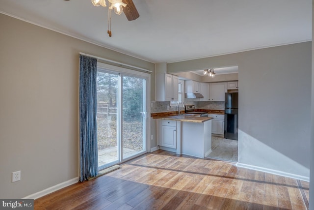 kitchen with wooden counters, decorative backsplash, electric range, light hardwood / wood-style floors, and white cabinetry