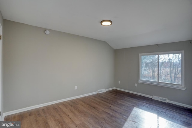 spare room with dark wood-type flooring and lofted ceiling