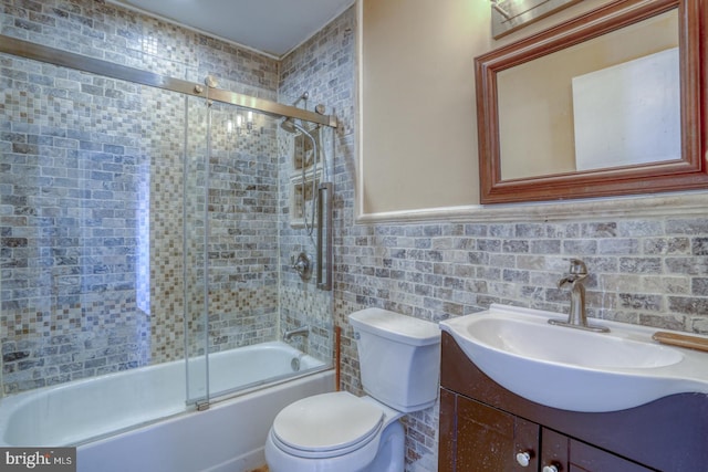 full bathroom with vanity, toilet, tile walls, and combined bath / shower with glass door