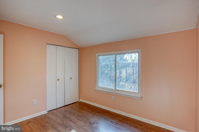 unfurnished bedroom with a closet, light hardwood / wood-style floors, and lofted ceiling