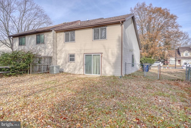 rear view of house with central AC unit and a lawn