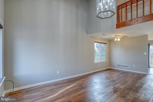 empty room with a high ceiling, hardwood / wood-style flooring, and ceiling fan