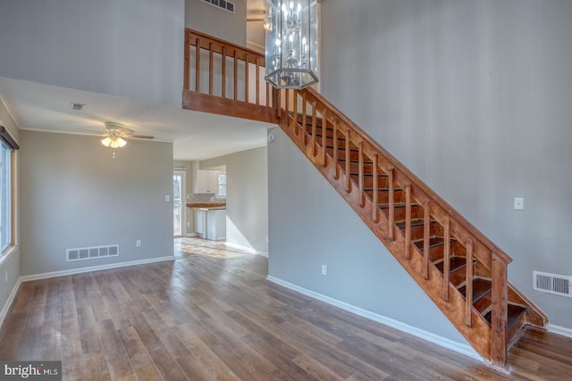 stairway featuring hardwood / wood-style floors and ceiling fan with notable chandelier