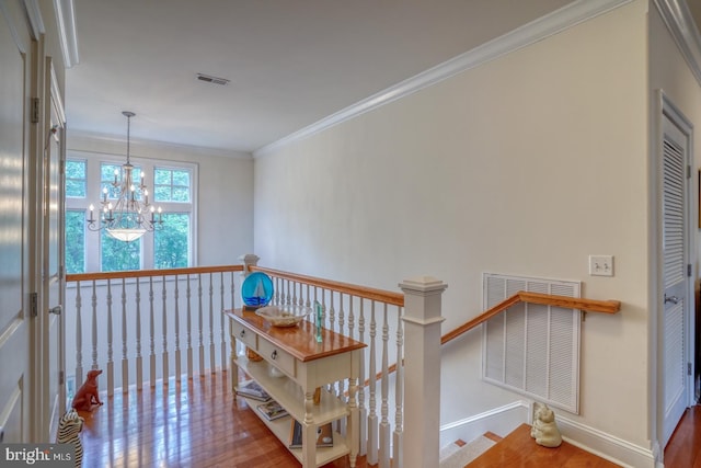 hall with hardwood / wood-style floors, crown molding, and a notable chandelier