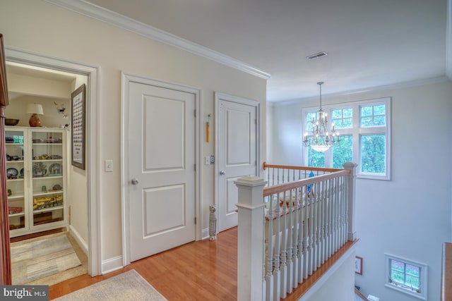 hall featuring light hardwood / wood-style flooring, a notable chandelier, and ornamental molding