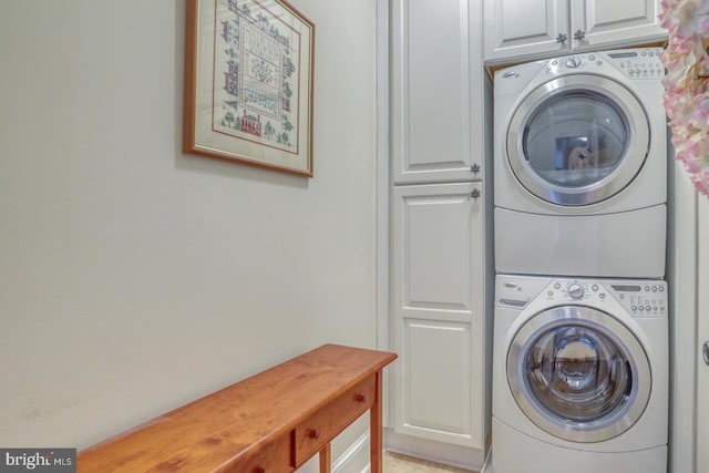 clothes washing area featuring cabinets and stacked washer and dryer