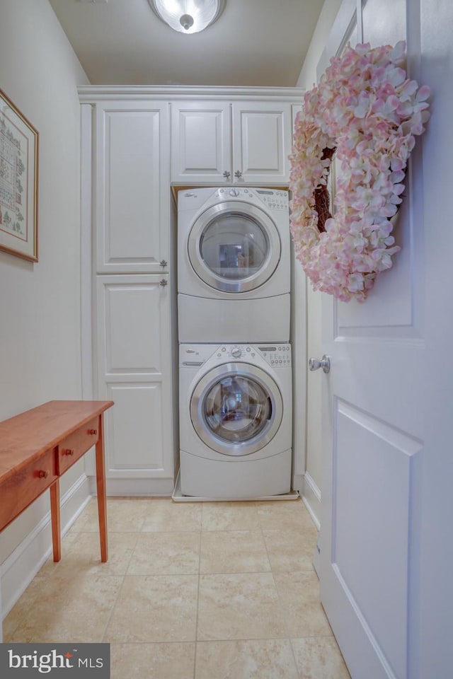 washroom featuring cabinets, stacked washer / drying machine, and light tile patterned flooring