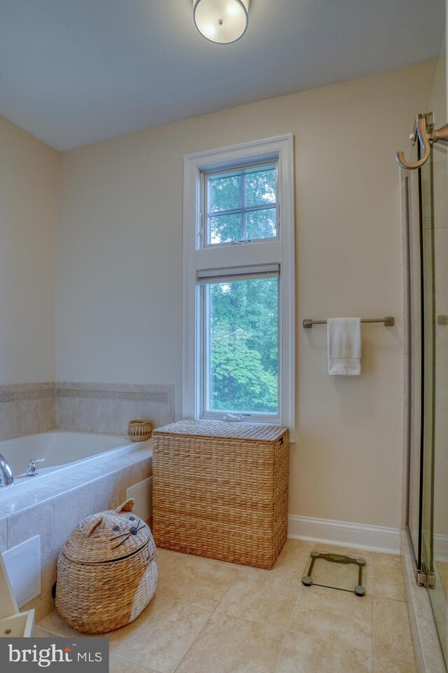 bathroom with tile patterned flooring and tiled bath