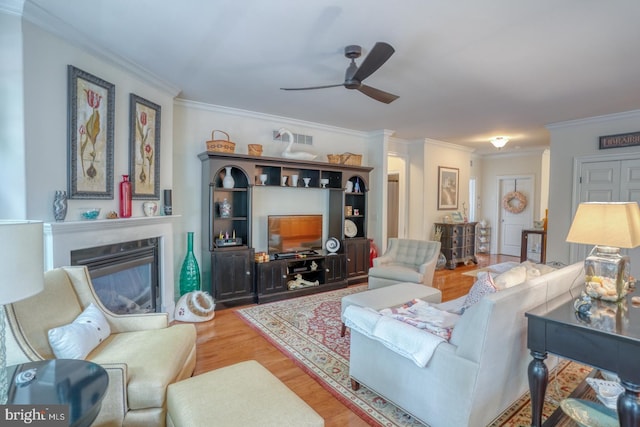 living room with hardwood / wood-style flooring, ceiling fan, and crown molding