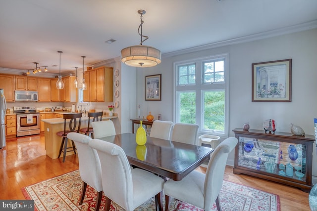 dining room featuring light hardwood / wood-style floors, ornamental molding, and sink