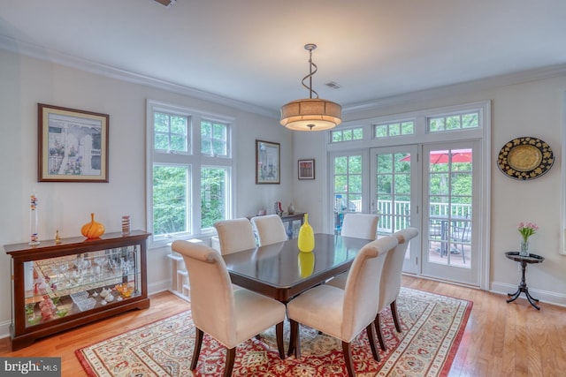 dining area with a healthy amount of sunlight, light wood-type flooring, and ornamental molding