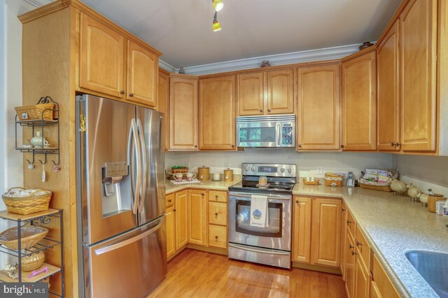 kitchen featuring light wood-type flooring, ornamental molding, and appliances with stainless steel finishes