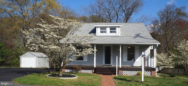 view of front facade featuring a front yard, a porch, a garage, and an outdoor structure