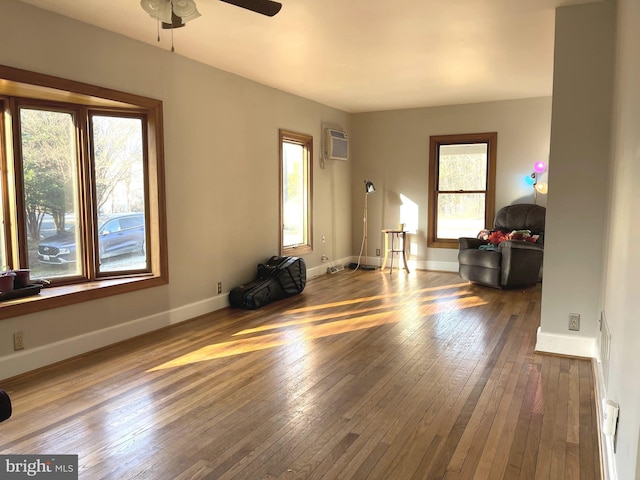 unfurnished living room featuring ceiling fan, wood-type flooring, and an AC wall unit