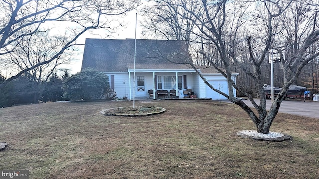 view of front of house featuring covered porch, a garage, and a front lawn