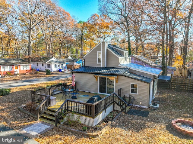 back of house with an outdoor fire pit and a deck