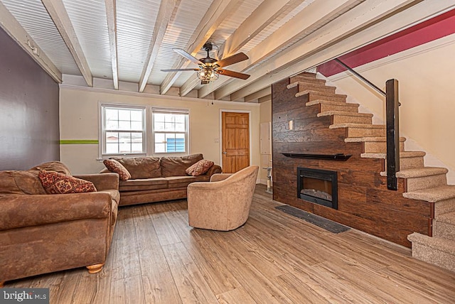 living room with ceiling fan, beam ceiling, a fireplace, and wood-type flooring