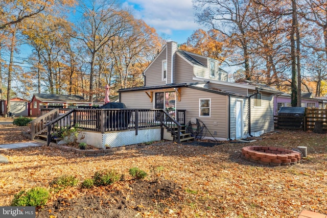 back of property featuring an outdoor fire pit and a deck