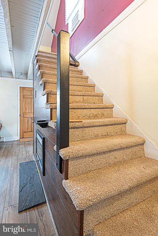 stairs featuring beam ceiling and hardwood / wood-style flooring