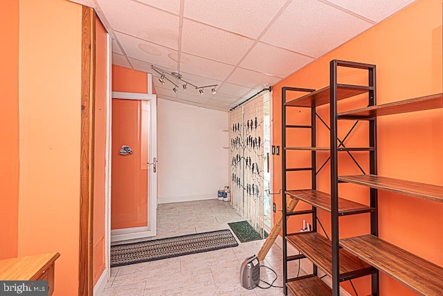 corridor featuring a paneled ceiling and track lighting