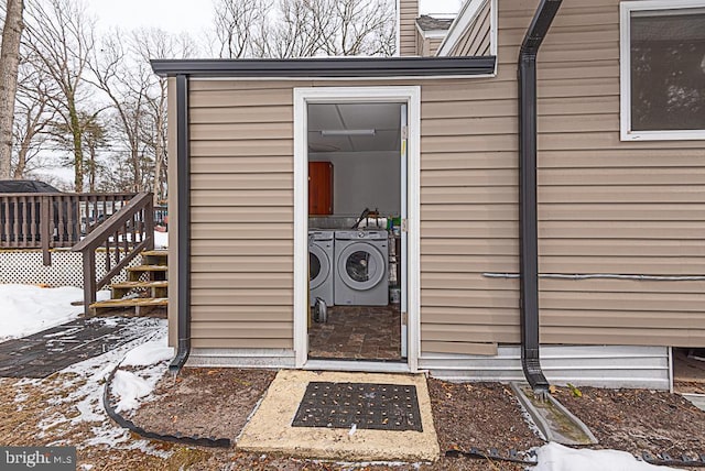 snow covered property entrance featuring a wooden deck and washer and dryer