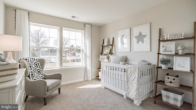 bedroom with multiple windows, light carpet, and a crib