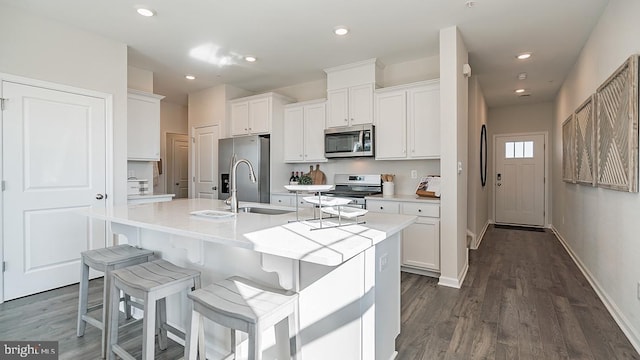 kitchen featuring white cabinetry, dark hardwood / wood-style flooring, an island with sink, and appliances with stainless steel finishes